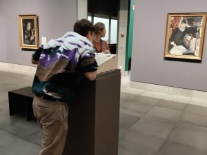 man leaning over to talk to painting with AI in museum