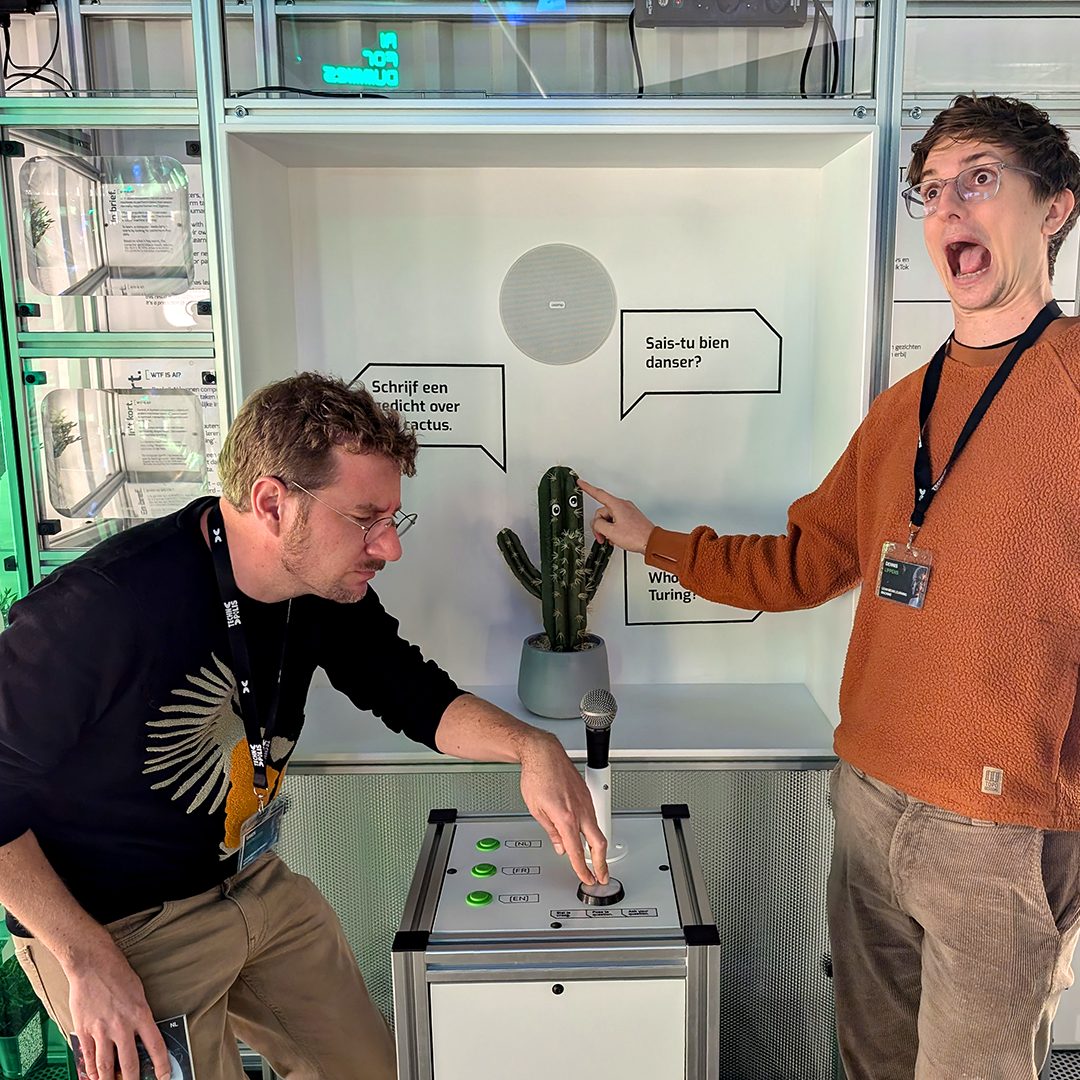 Two visitors laughing at the cactus exhibit, one pretending to be stung
