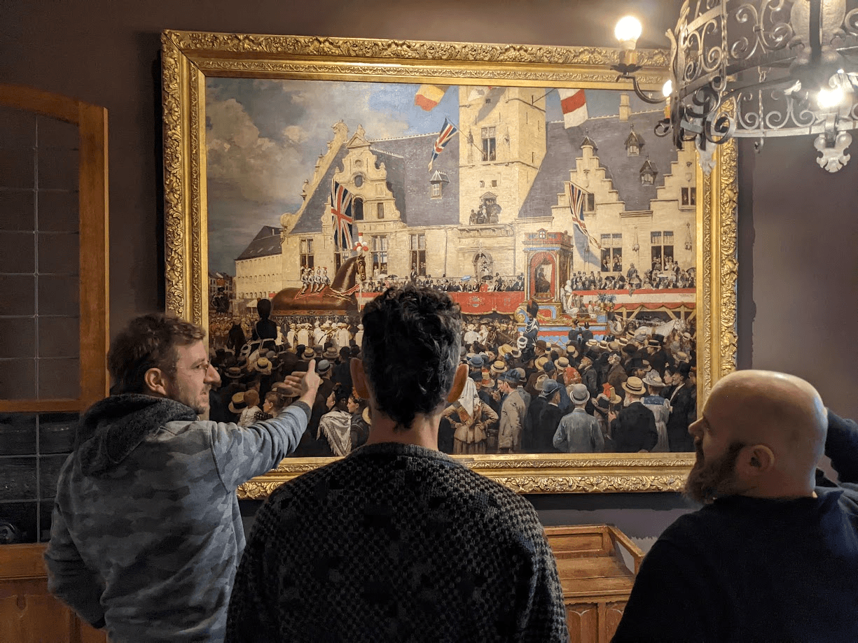 A visitor pointing at a detail of the Ros Beiaard painting while two others look on