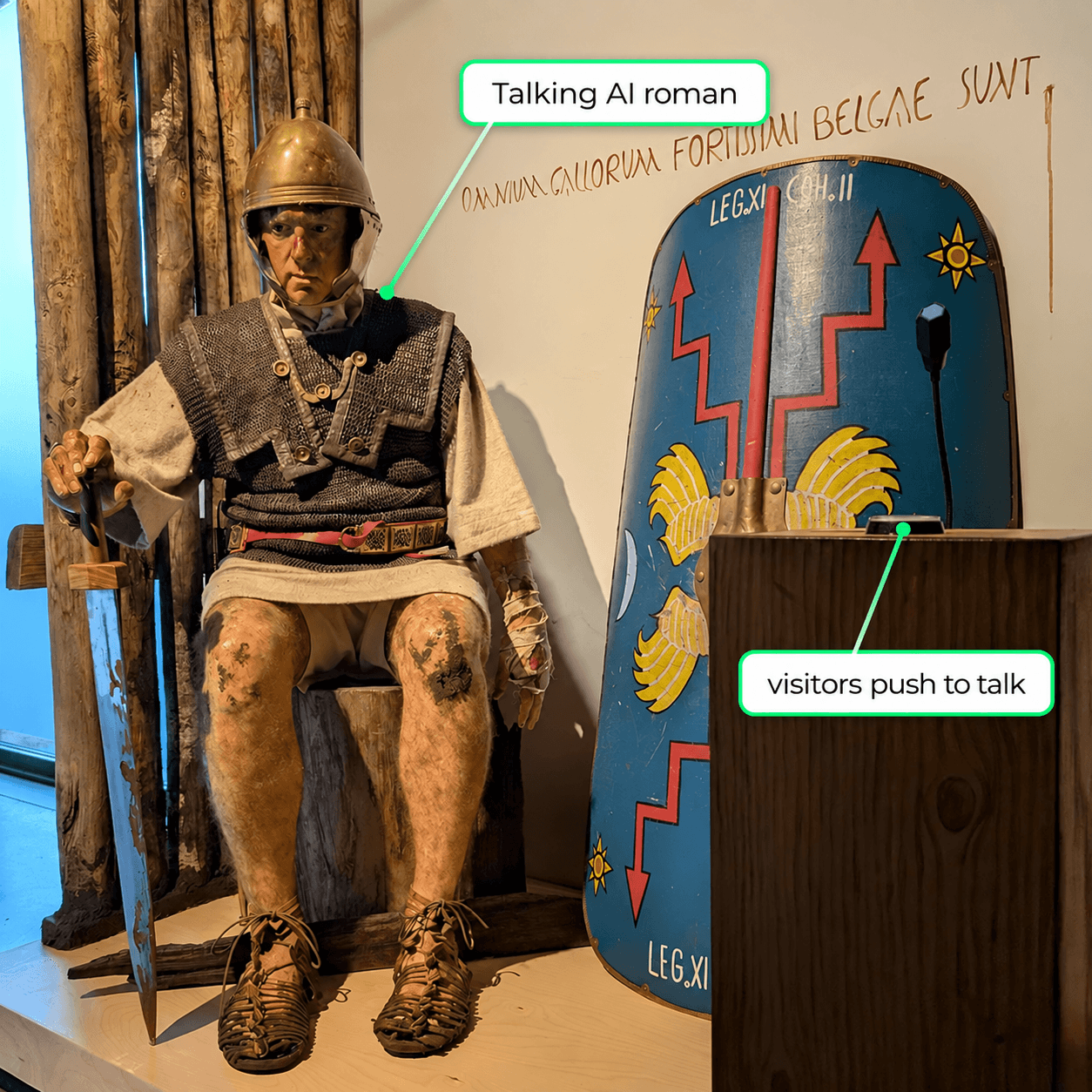 Quintus, the seated talking AI Roman soldier at the Archeocentrum Velzeke, next to the wooden stand with the push-to-talk button and microphone