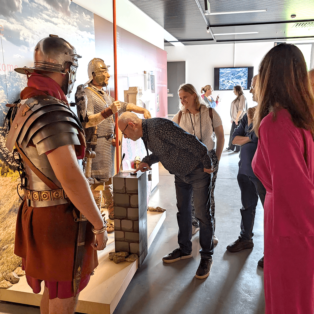 A visitor holds the button and asks a question to the AI Roman soldier in the Archeocentrum Velzeke