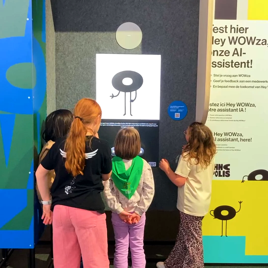 Four children at the heyWowza Talking Point kiosk at Technopolis, one pressing the button