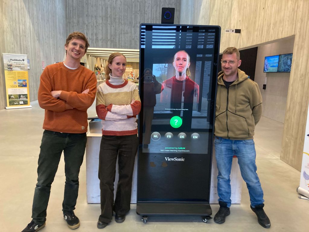 photo of the digital front desk with the colleague who posed for it next to together with the creator