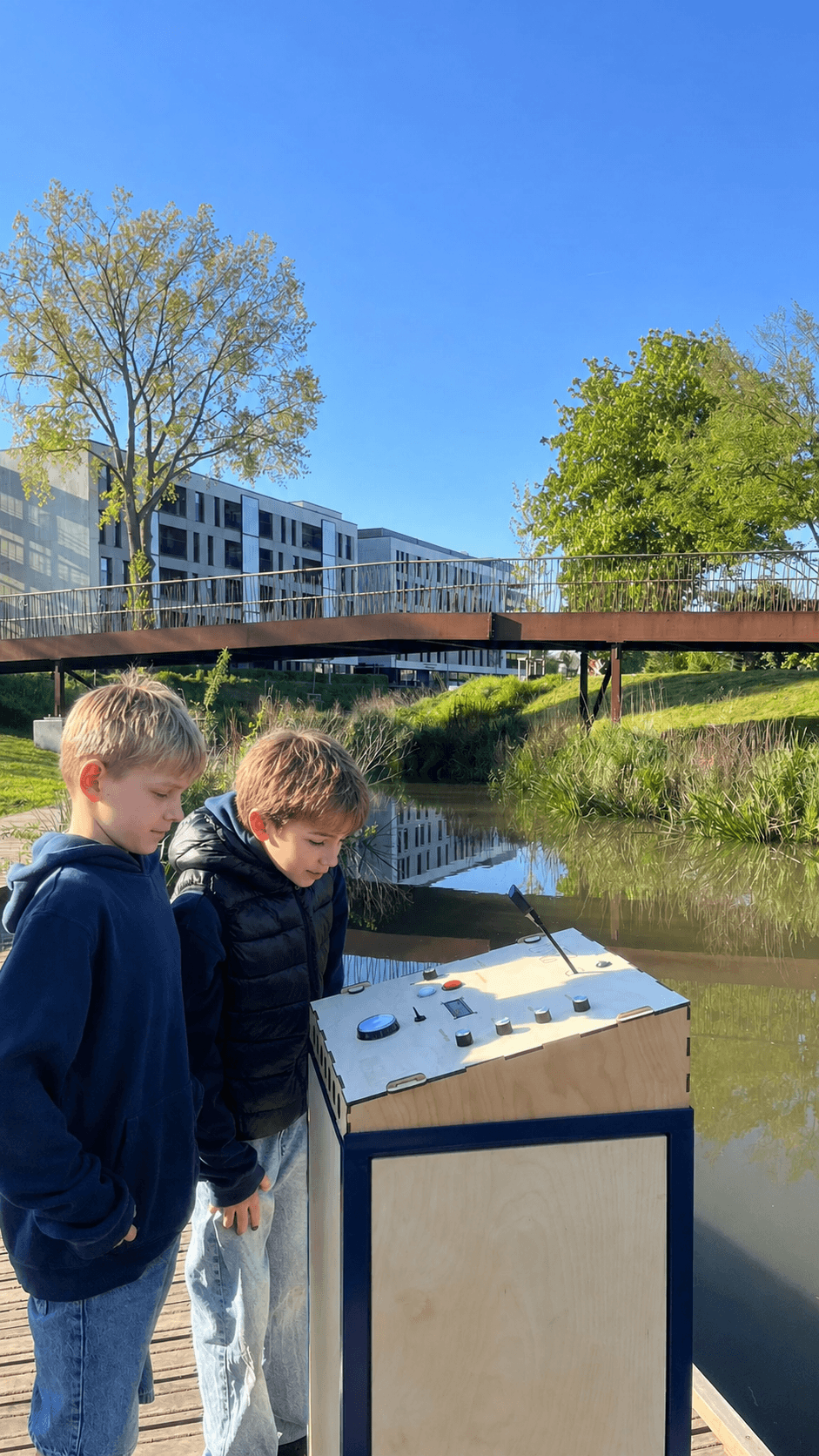 Two boys talking to the Waterpraatpaal on a bridge over the Bruges Reien